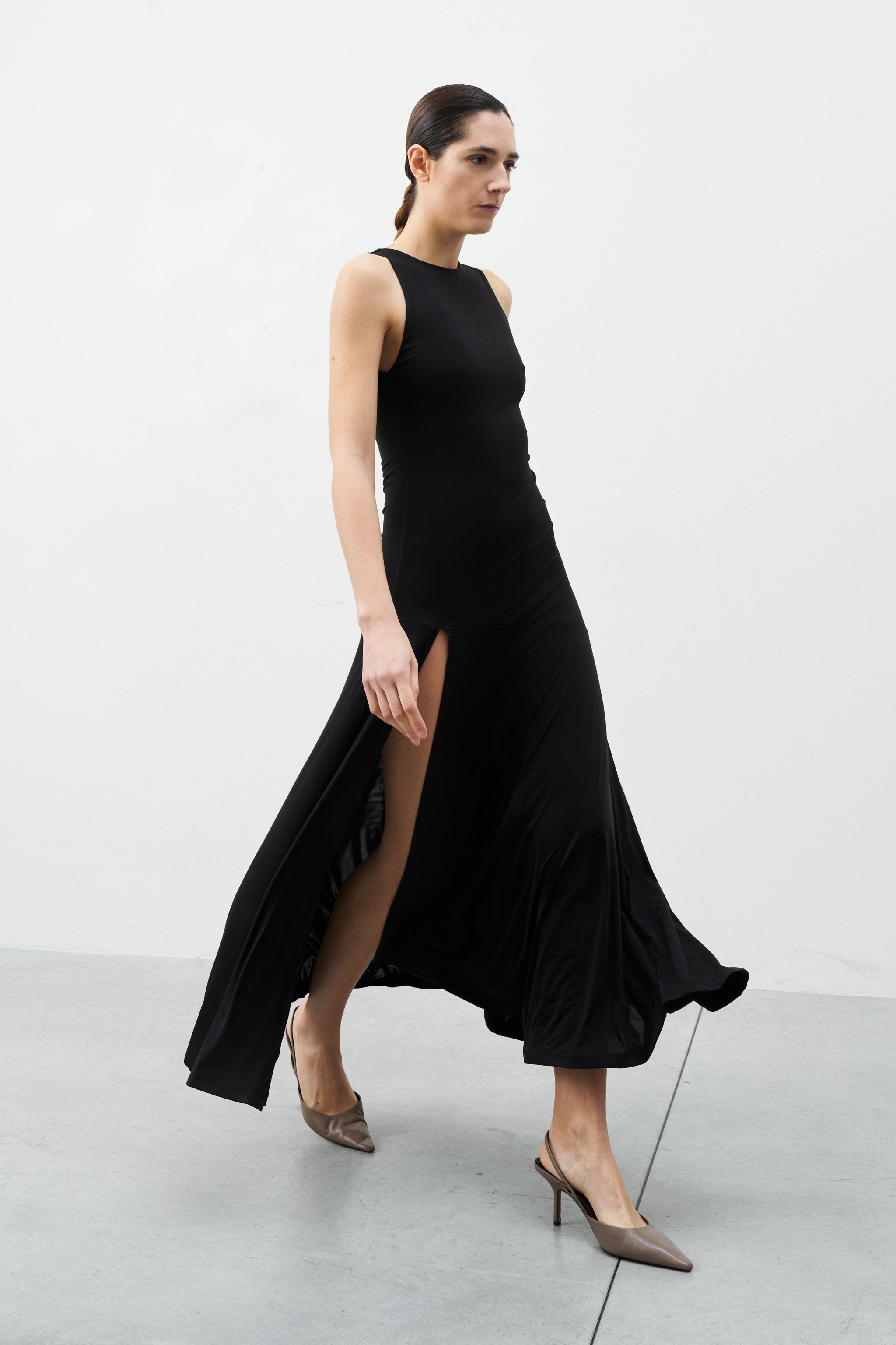 Mirage Dress black sleeveless midi dress walking view flowy hem stitching detail elegant dress