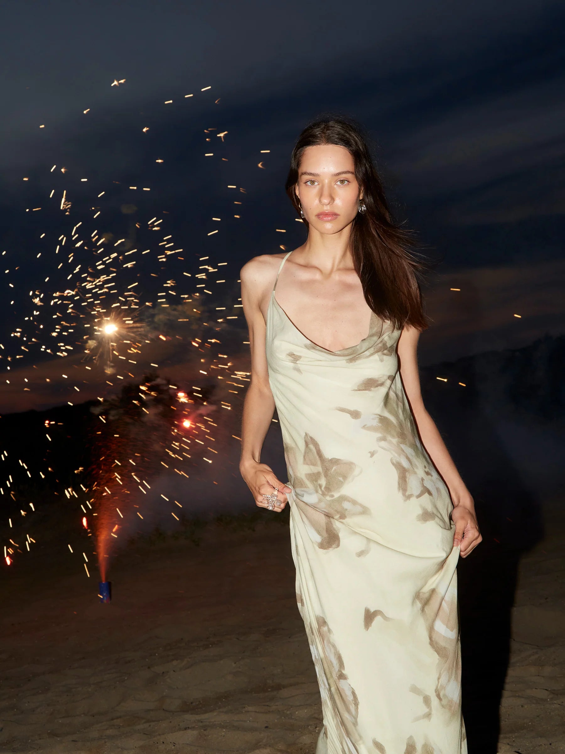 Beige floral printed maxi dress styled at night with open back and crisscross straps, elegant summer look