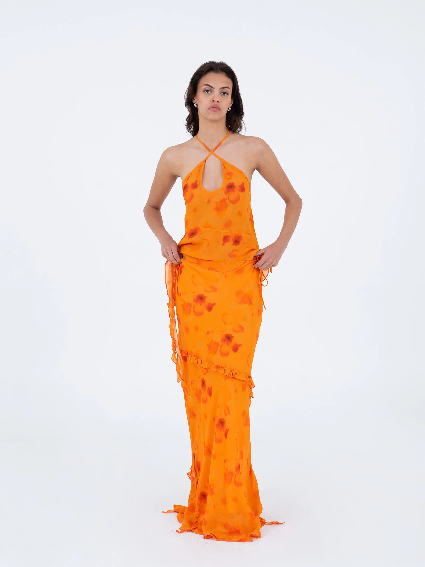 Orange long low rise skirt model pose showing decorative ruffles adjustable side straps and lightweight viscose texture